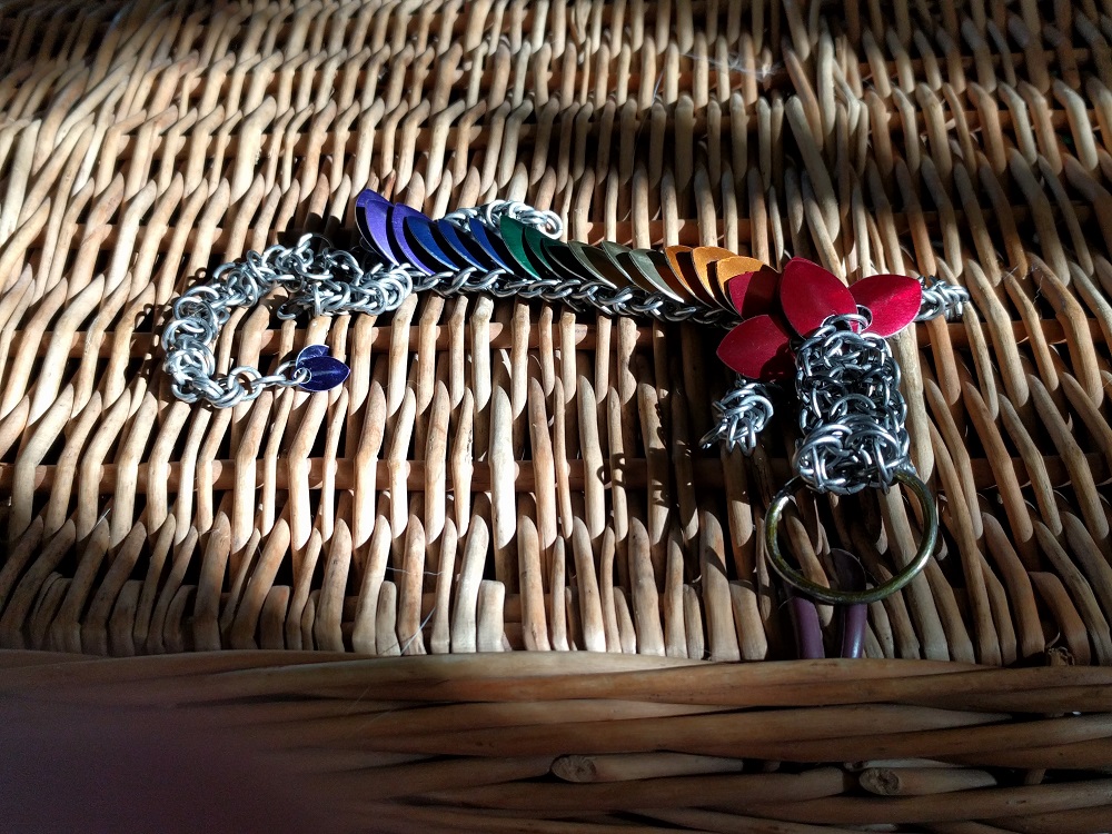 A rainbow striped dragon sitting in the sun on a wicker basket.