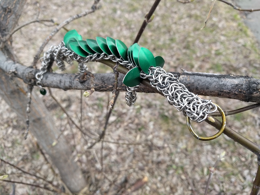 A green dragon laying on top of the tree of a branch.