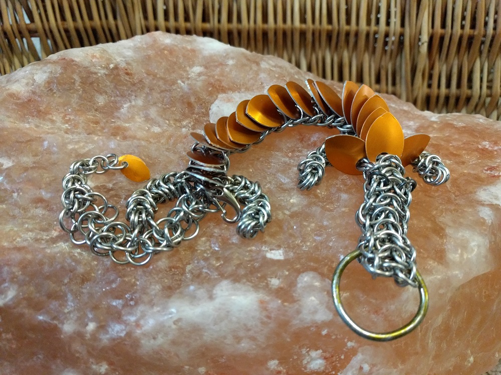 An orange dragon laying on a Himalayan salt rock in front of a wicker basket.