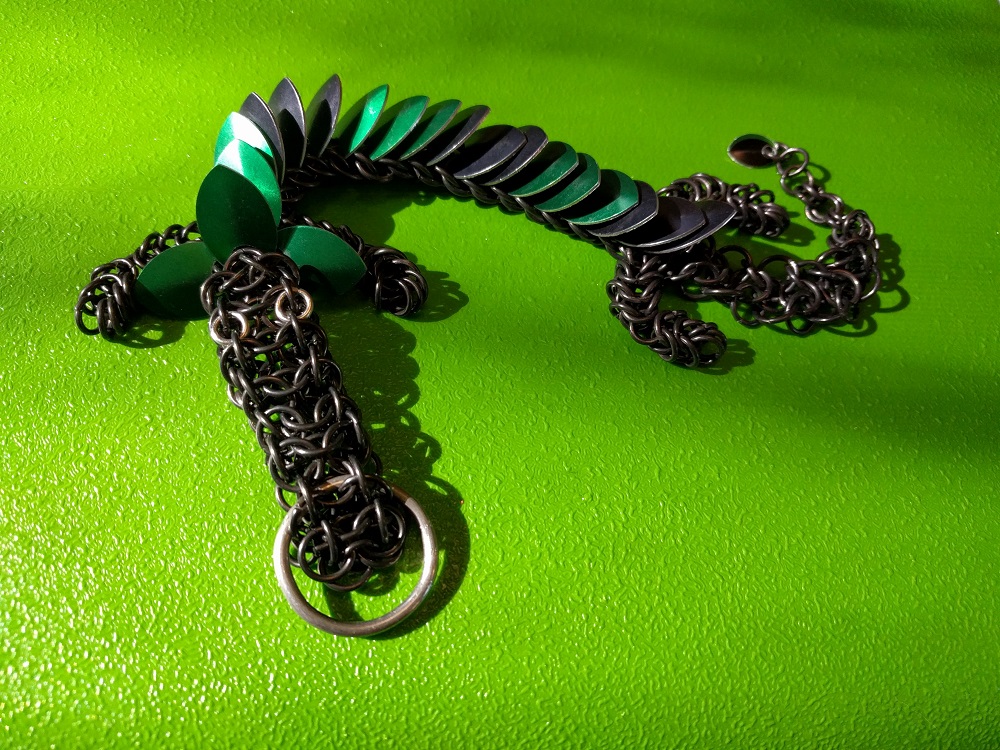 A green and black striped dragon with black rings laying on a bright green plastic surface.