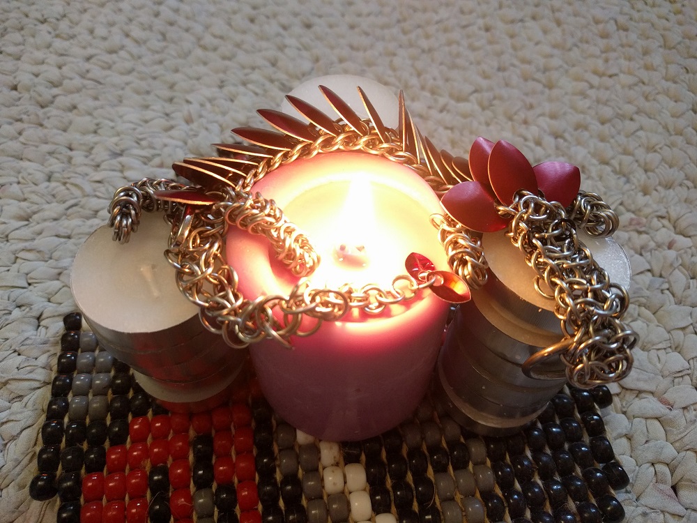 A red dragon wrapped around a large lit pink candle, which itself is surrounded by stacks of fresh tea lights.