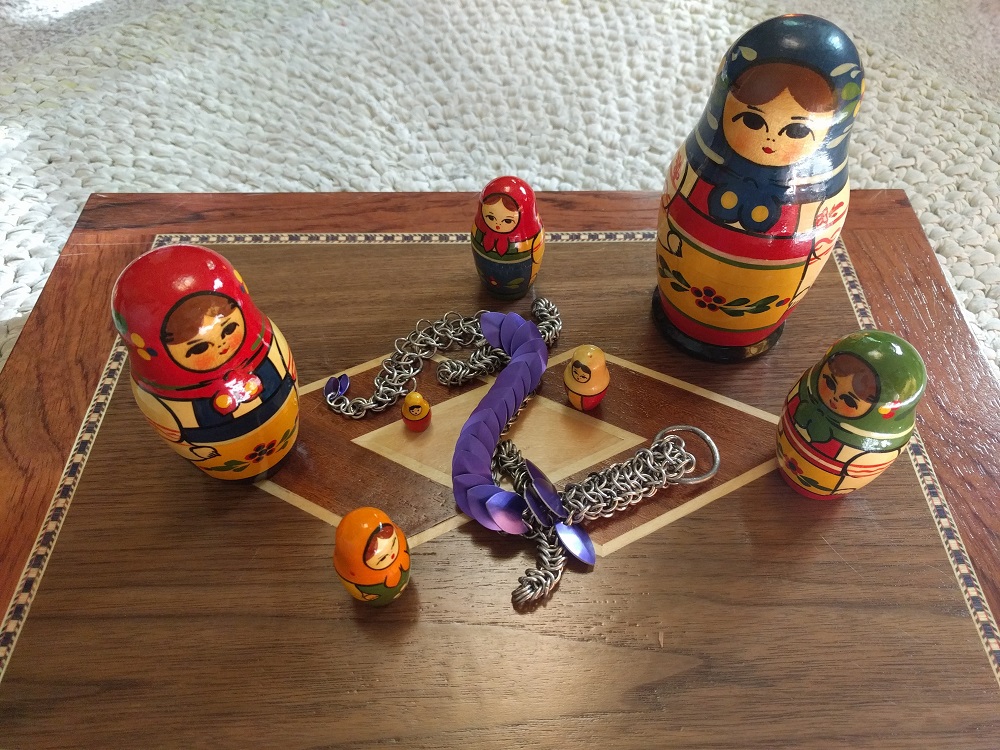 A purple dragon laying on a wooden box surrounded by the inner dolls of as nesting matryoshka doll.