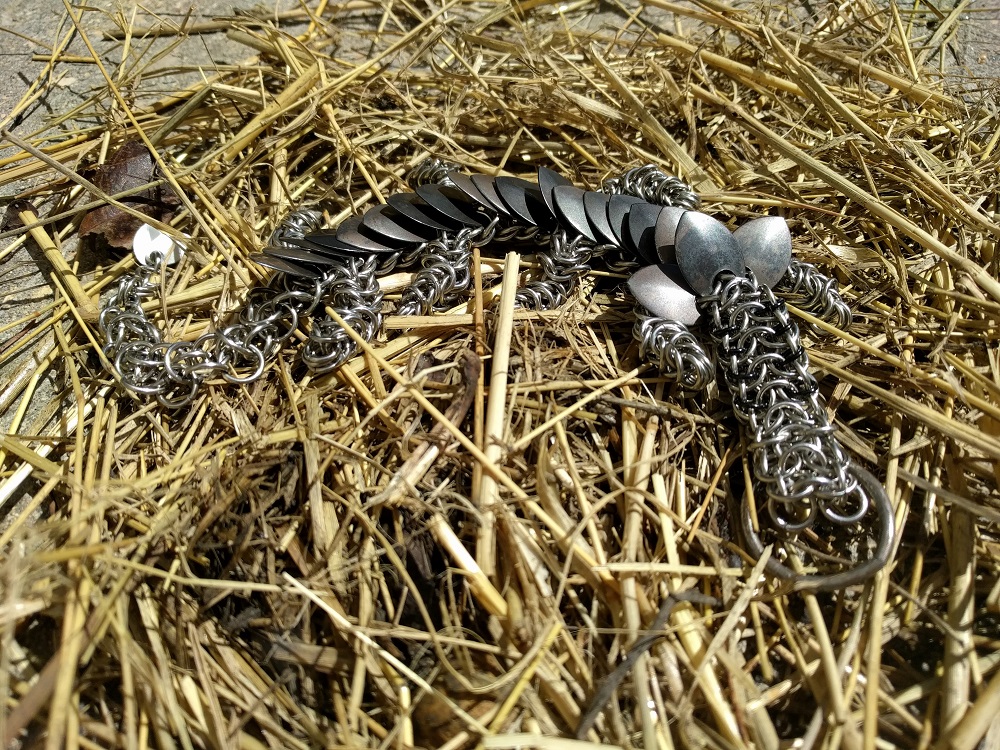 An eight eyed, eight legged black and dark grey striped dragon laying atop a pile of straw and leaves.