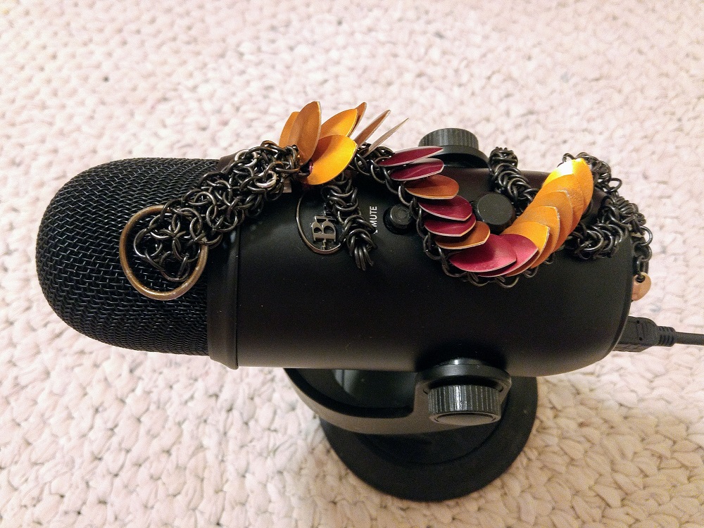 An orange and red striped dragon with black rings curled on top of a black microphone.