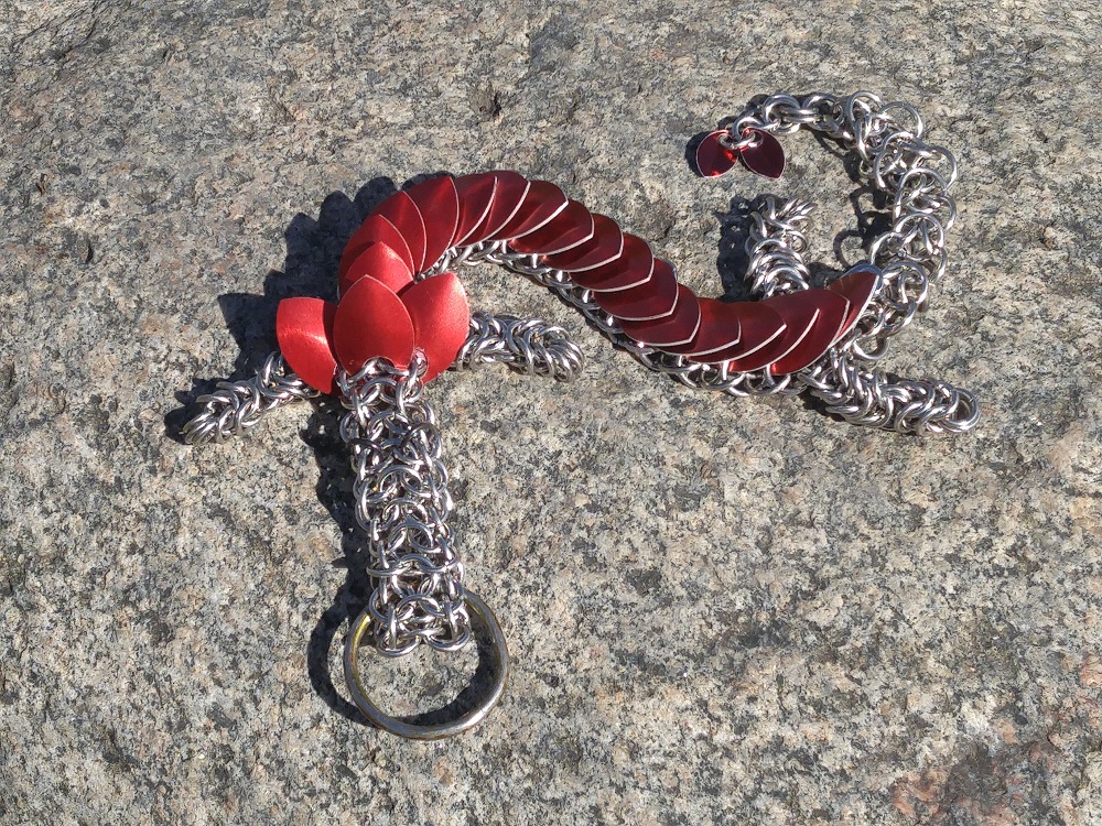 A red dragon laying on top of a big grey rock in the sun.