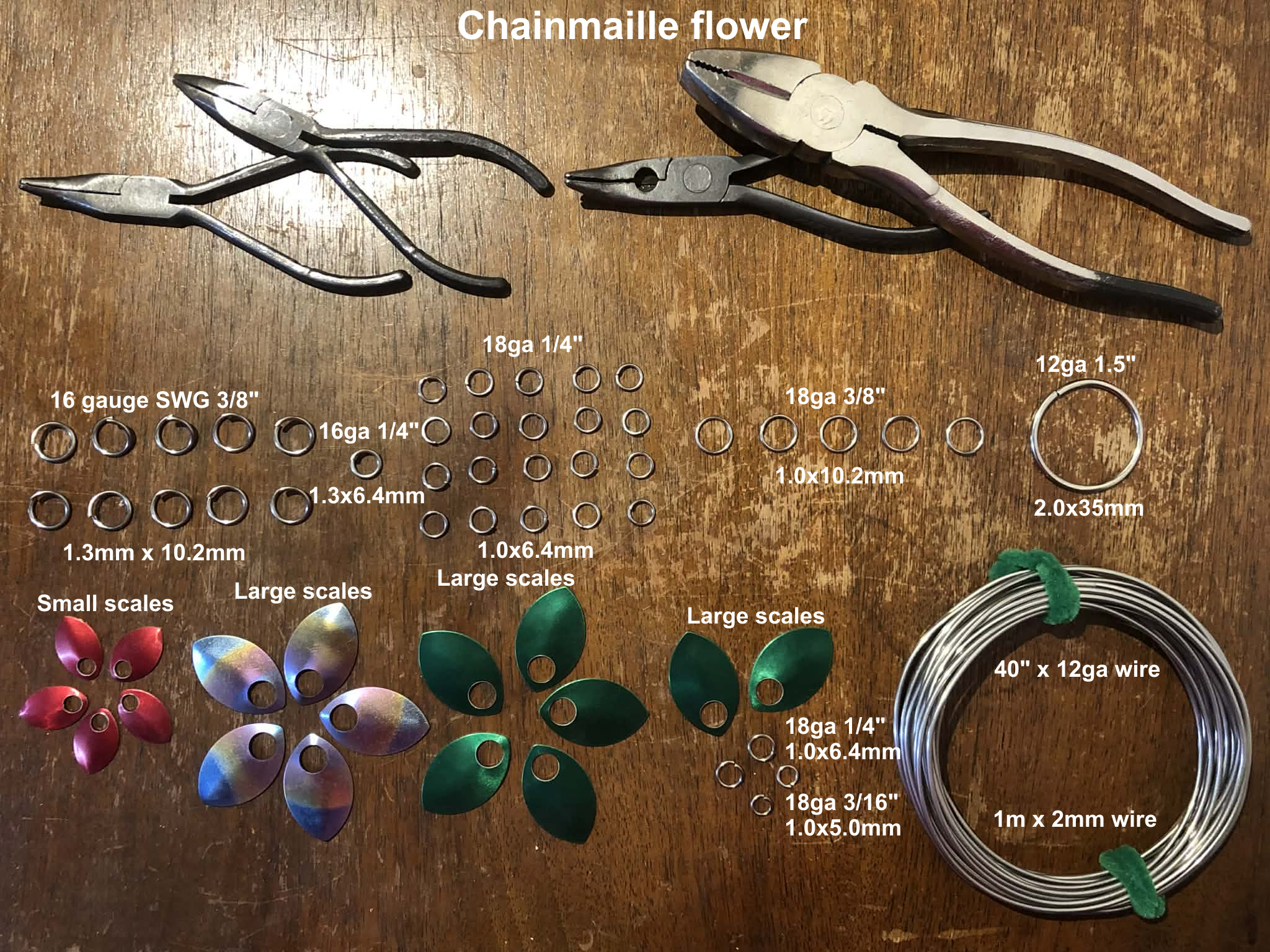 Three chainmaille flowers, created as a five petal chainmaille flower, made using large and small scales for the petals, large green scales behind the flower and as leaves down the stem.