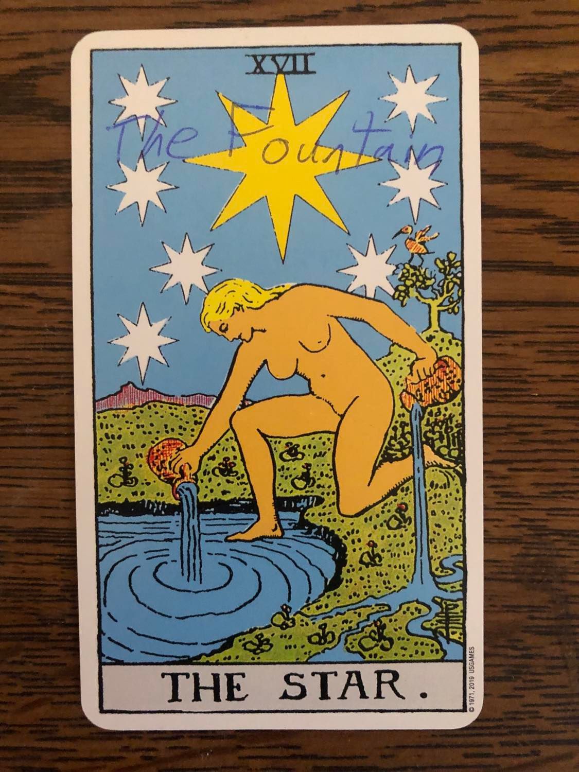 The star card with the fountain written on it, laying on a wooden desk.