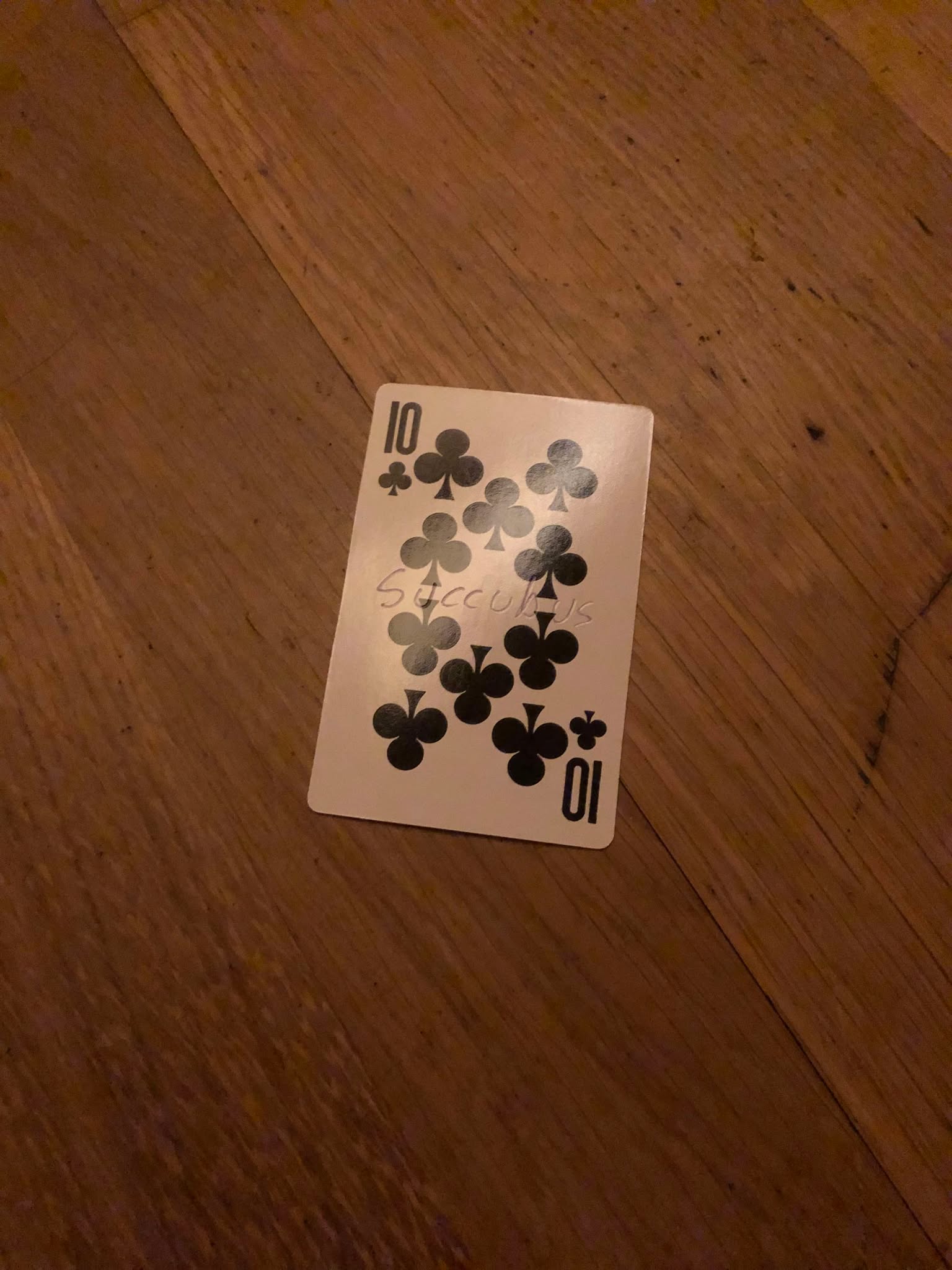 The ten of clubs, thrown to the floor in front of the creature.