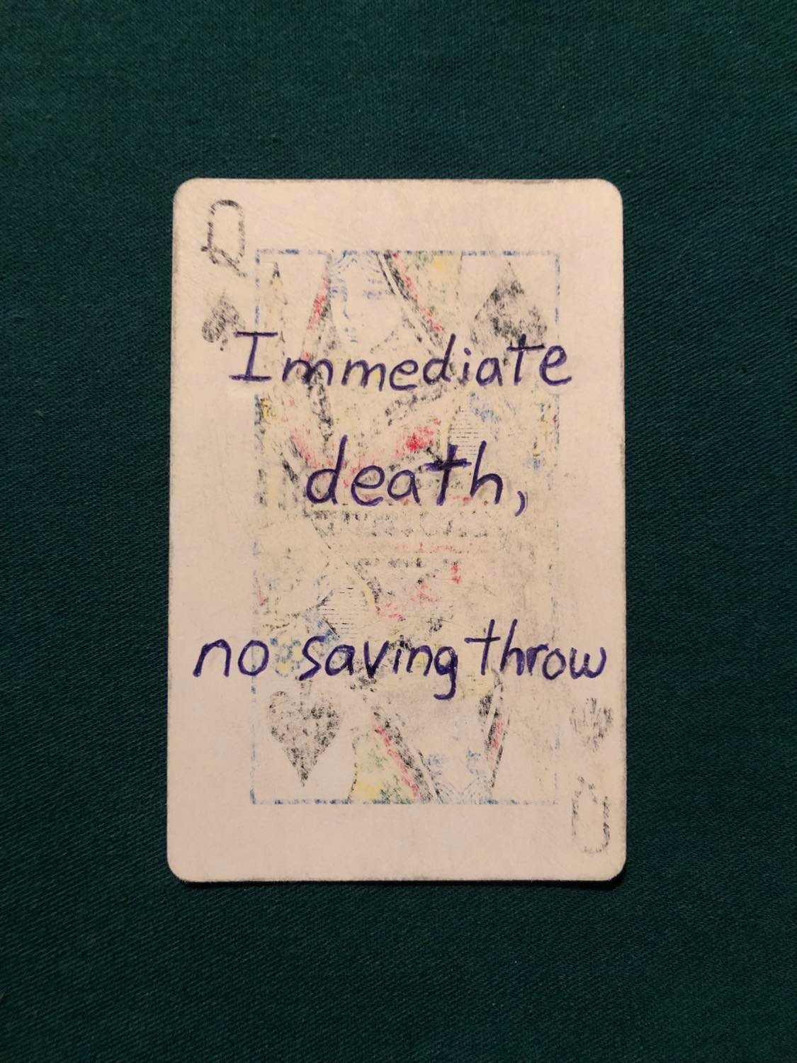 The queen of spades, laying on a green fabric.