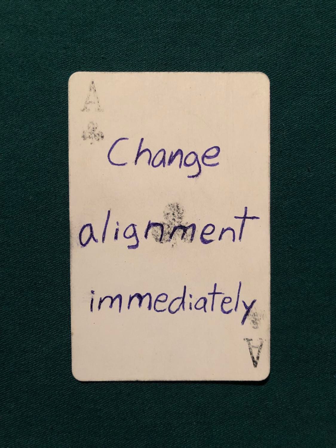 The ace of clubs, laying on a green fabric.