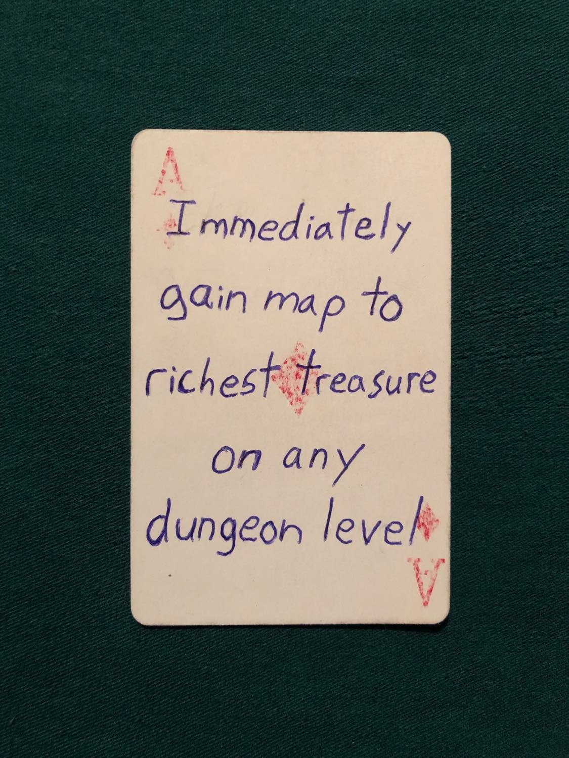 The ace of diamonds, laying on a green fabric.