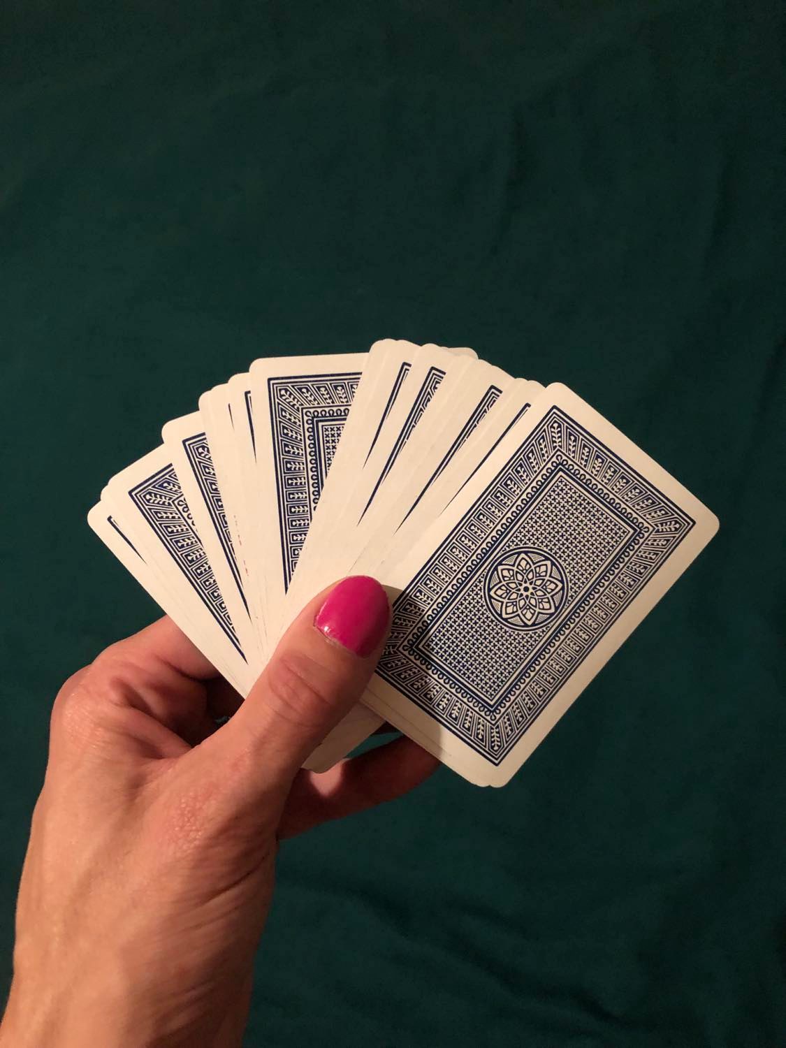 The cards held out in front of you, the blue pattern on the back having the illusion of being a room when viewed from above, with a simple mandala in the center. The cards are loosely spread out, as you ponder whether or not to draw.