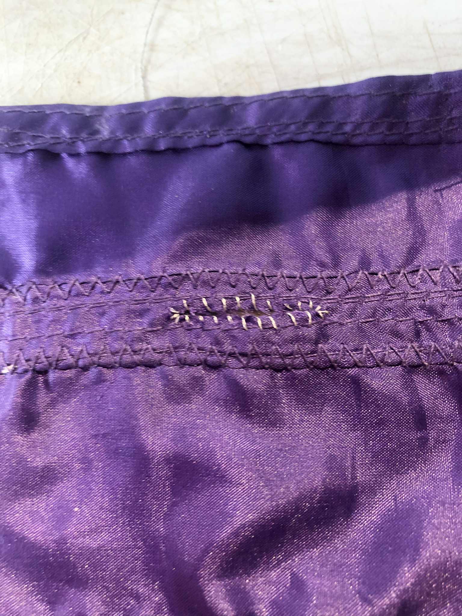 A closeup of a purple pocket slit, an extra sample piece for testing, with a single-stitch going all around the slit, rather than going over it double, which ended up looking too crammed and uneven.