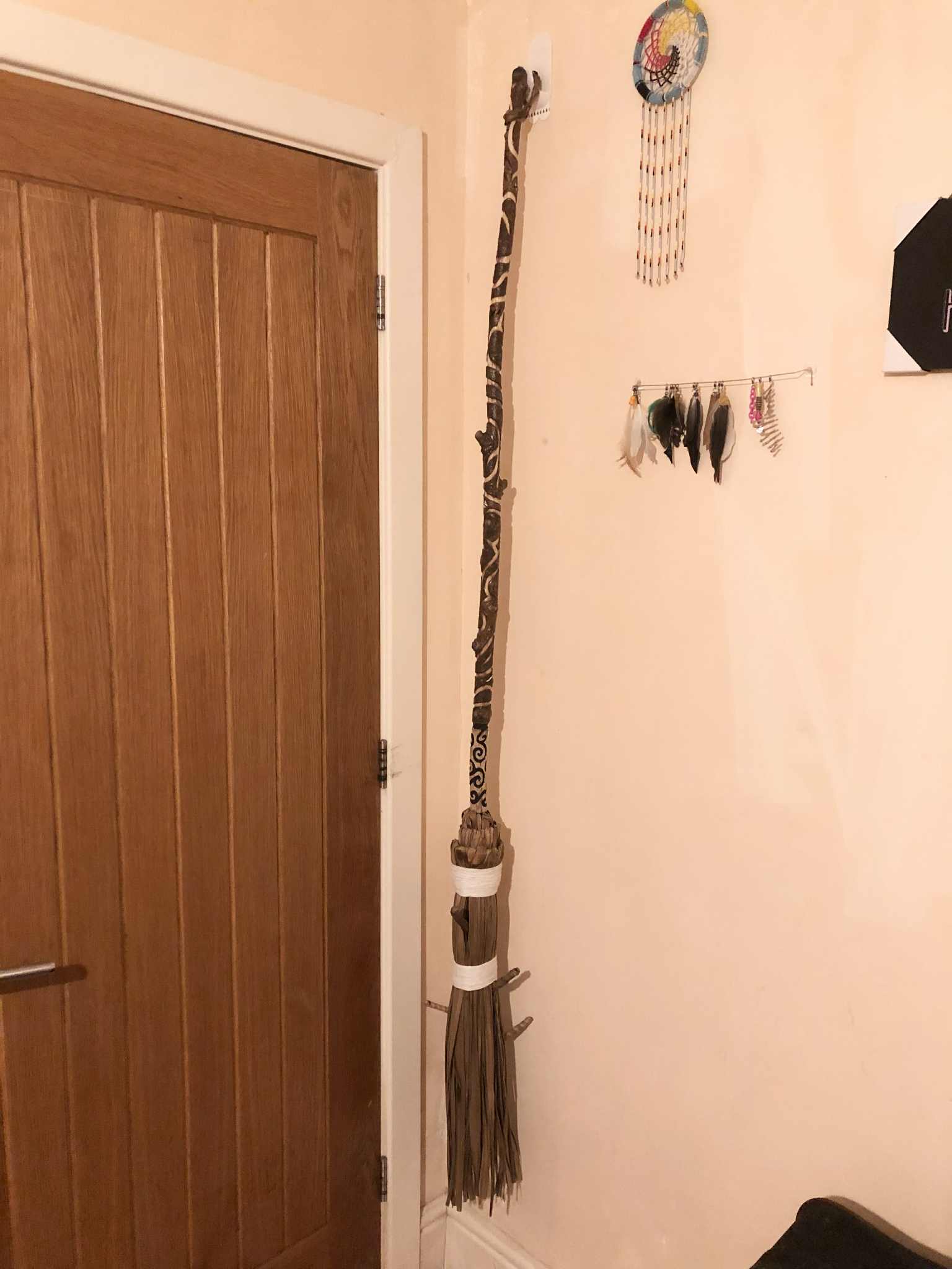 A besom, a witch's broom, made from an intricately carved wooden handle, and a head made from cabbage palm leaves, ready to sweep out the bad energy and sweep in the good.