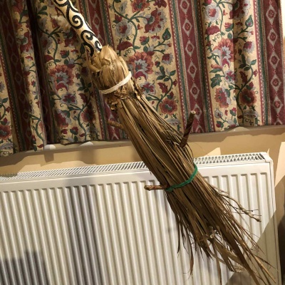 The head of a besom witch's broom, with a carved handle and palm leaf based head