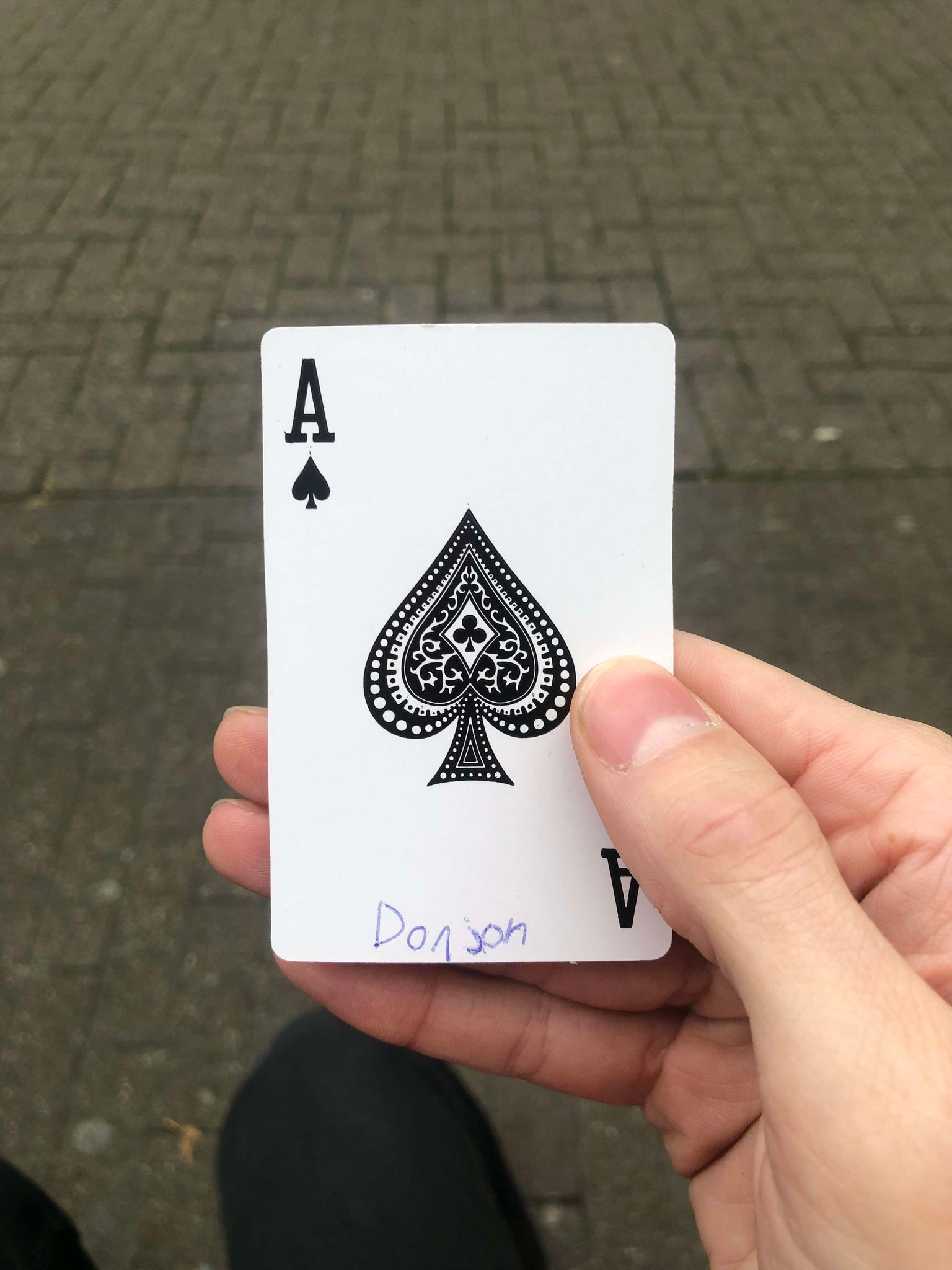 Sitting on a bench, a brick walkway in front of you, you hold the drawn card in front of you.