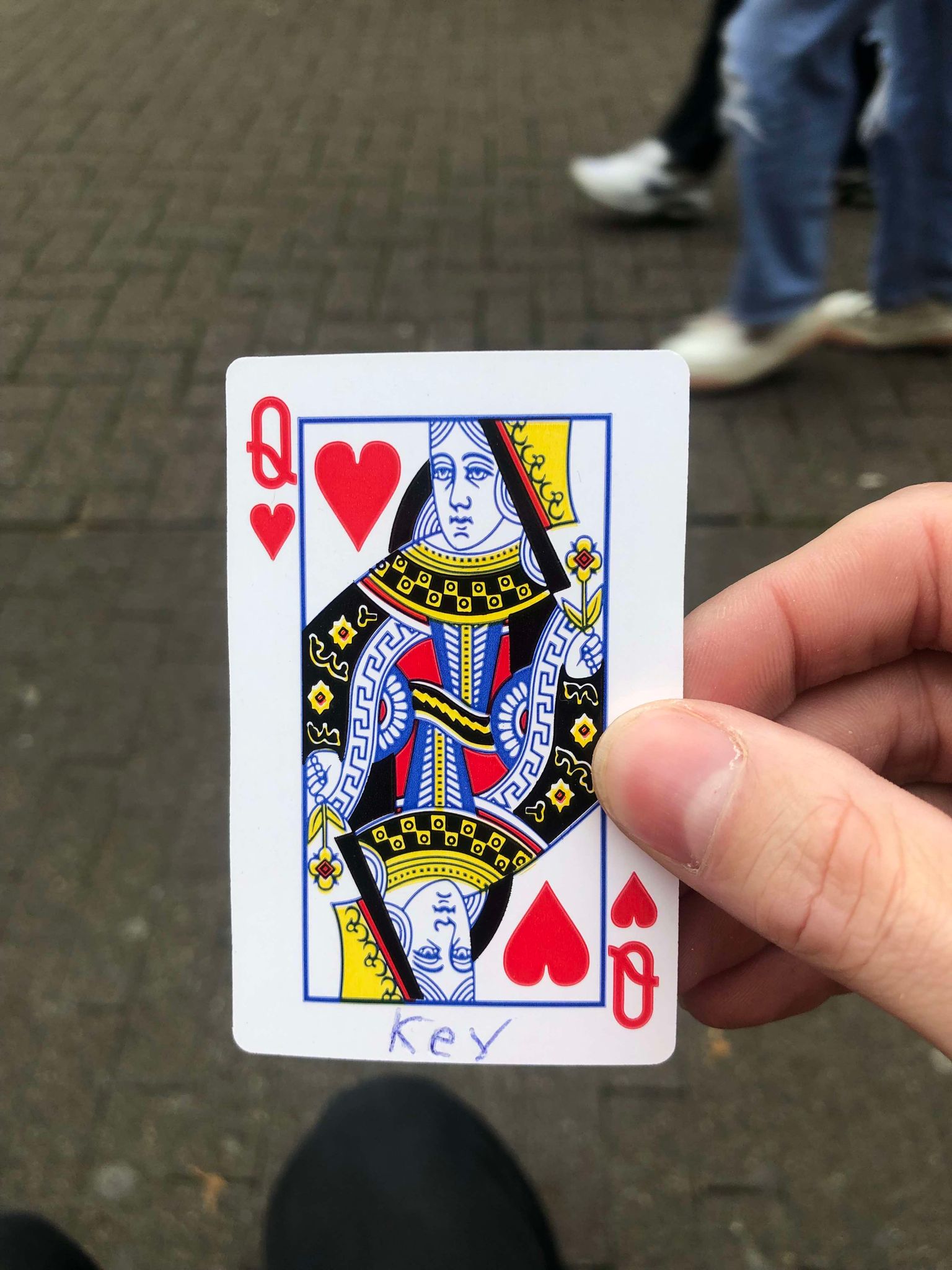 Sitting on a bench, a brick walkway in front of you, you hold the drawn card in front of you.