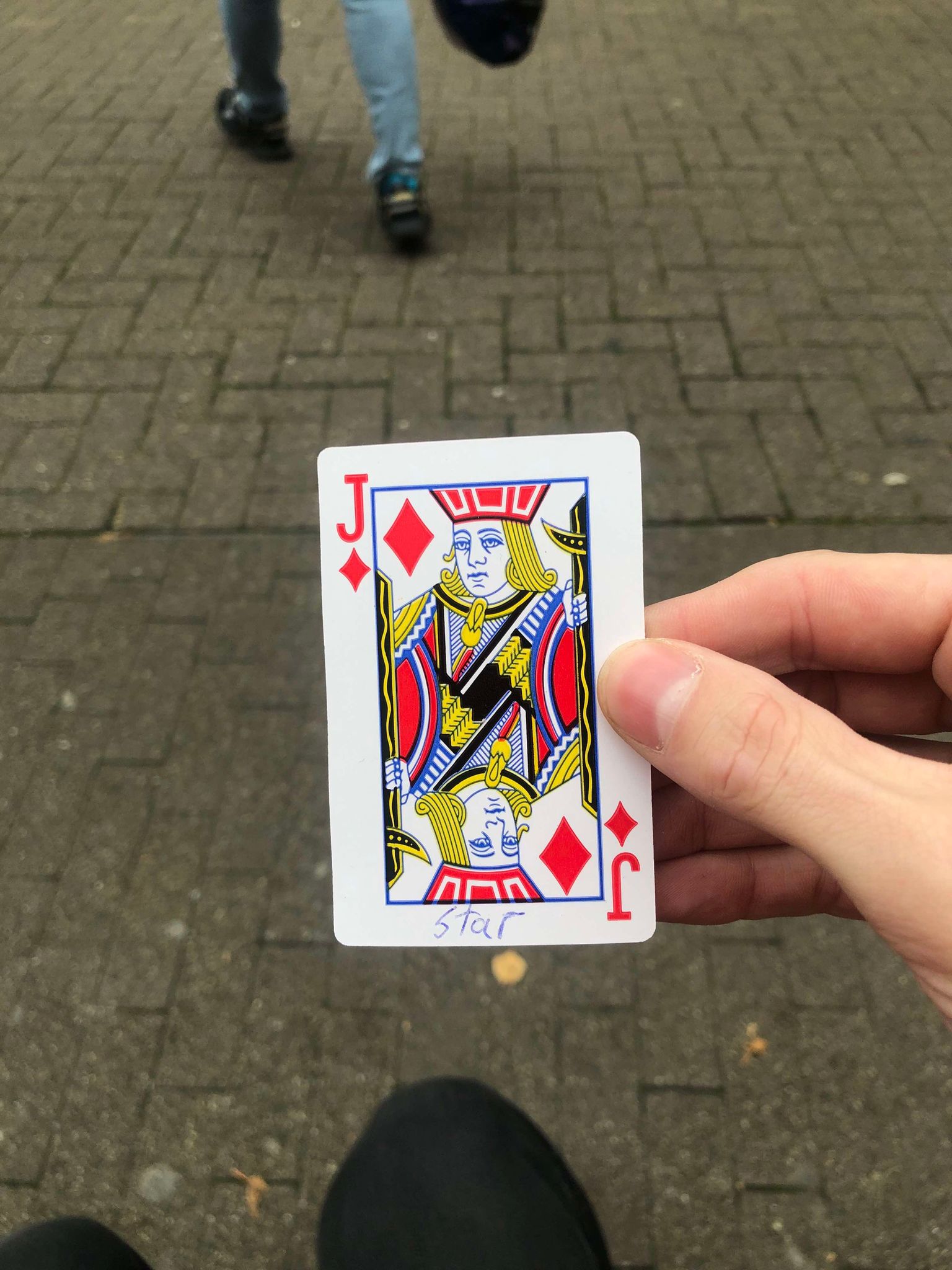 Sitting on a bench, a brick walkway in front of you, you hold the drawn card in front of you.