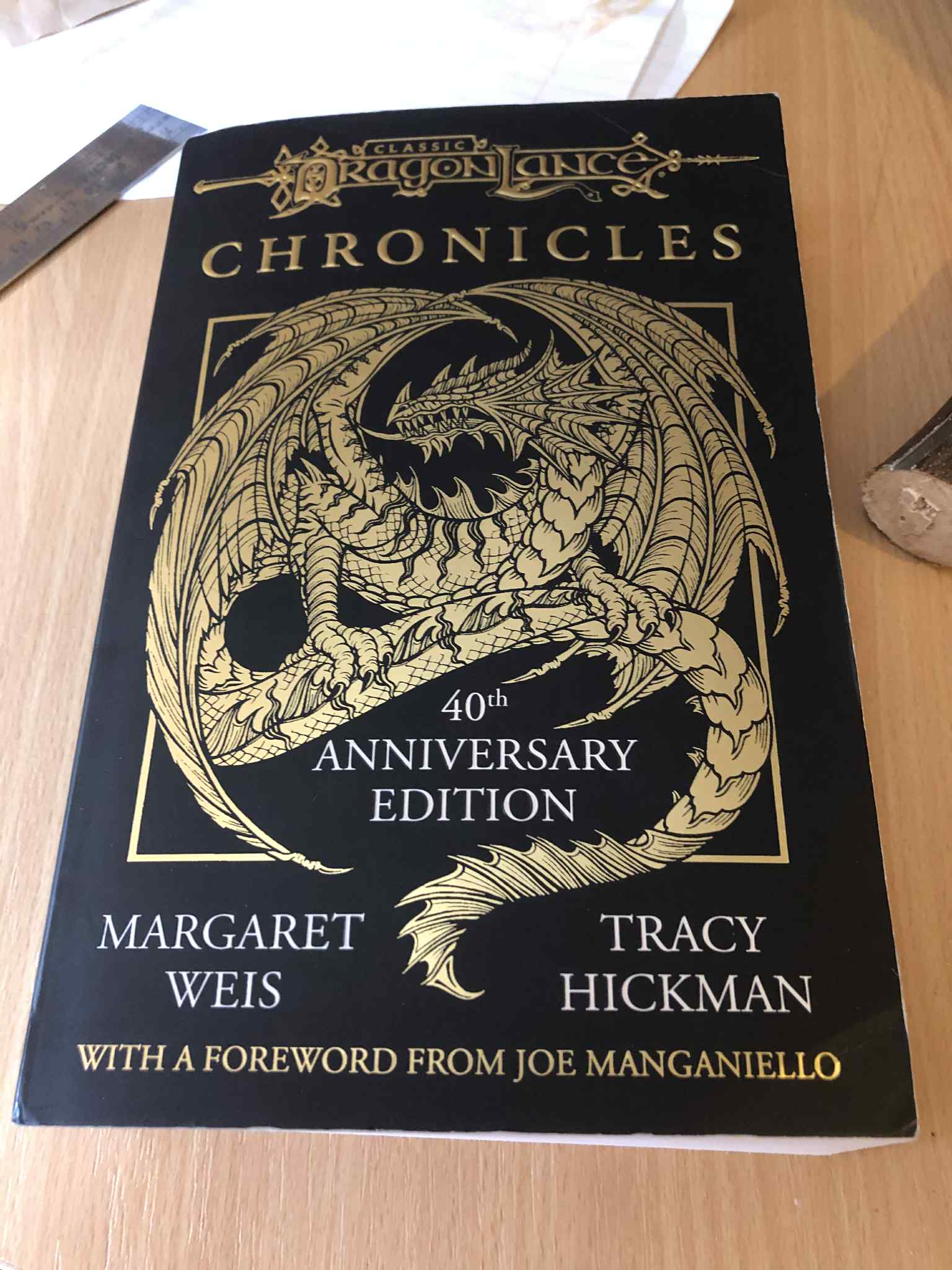 A thick three-book compilation of the first three Dragonlance chronicles novels. The cover is a gold illustrated dragon on a black background, stating it as the 40th year anniversary edition.
