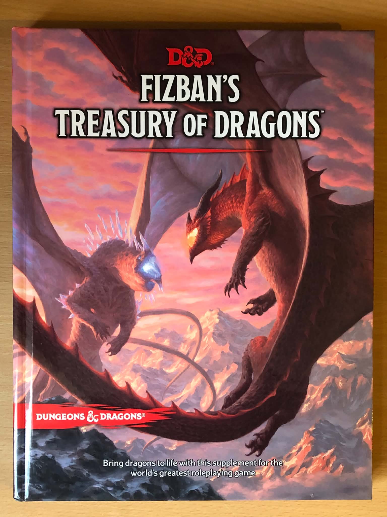 The book Fizban's Treasury of Dragons, depicting an ice and a fire dragon attacking eachother in the air over a mountainscape.