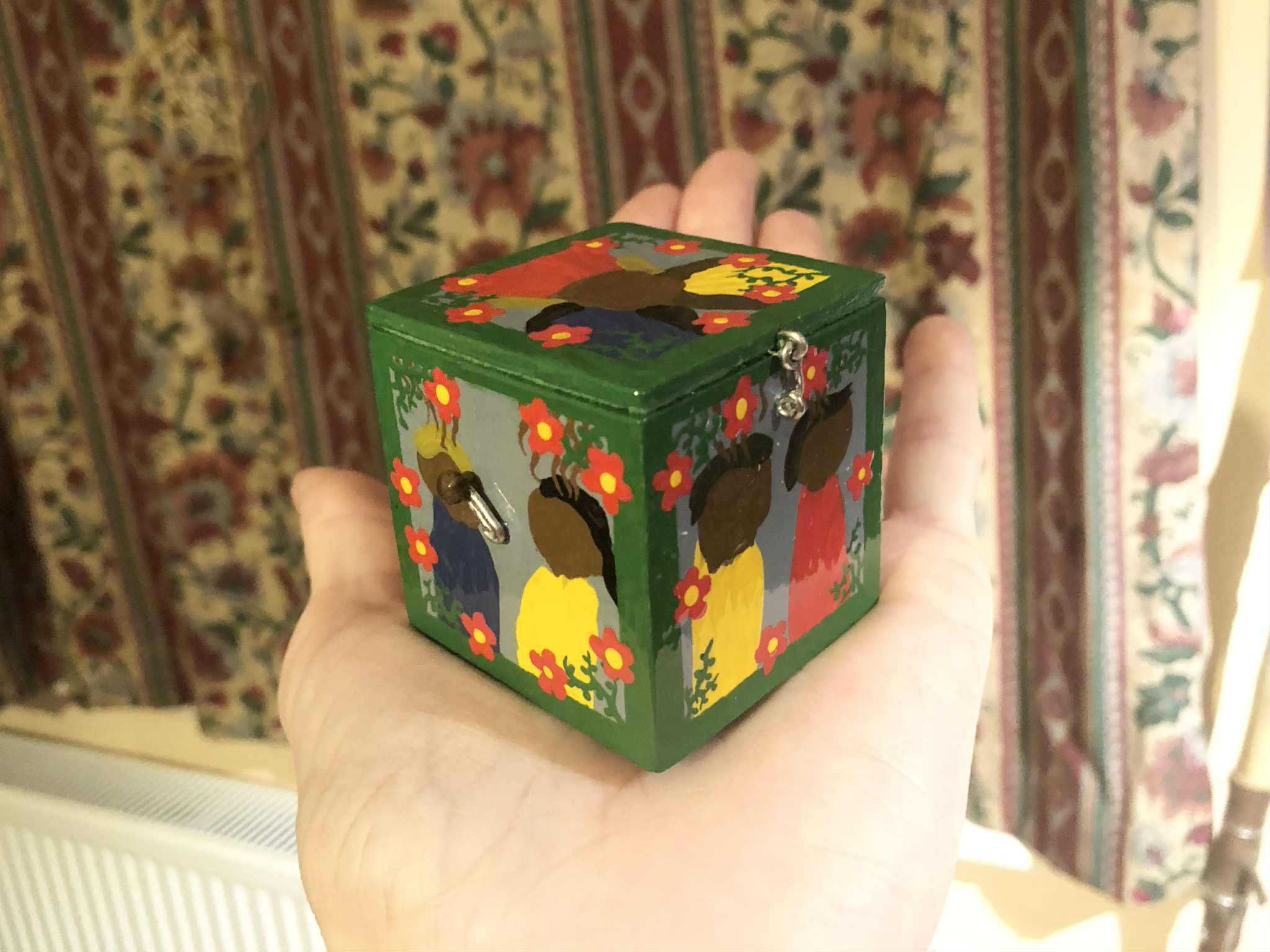 A painted wooden box sitting on an open palm. It's painted with figures on all sides, surrounded by green vinework and red flowers. A brown handled crank is on one side of the box. A Cube of Summoning, a Dungeons and Dragons item, what could be released by opening it?