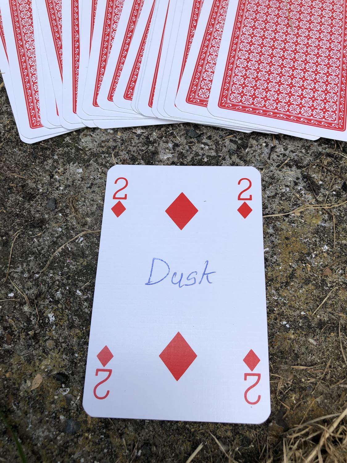 The two of diamonds with the word Dusk written on it, laying on the bridge support.