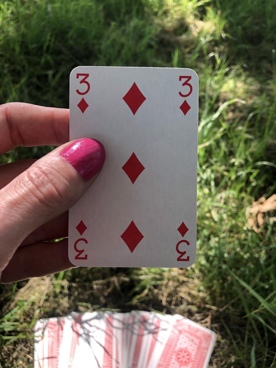 The three of diamonds, held up from the drawn out cards.