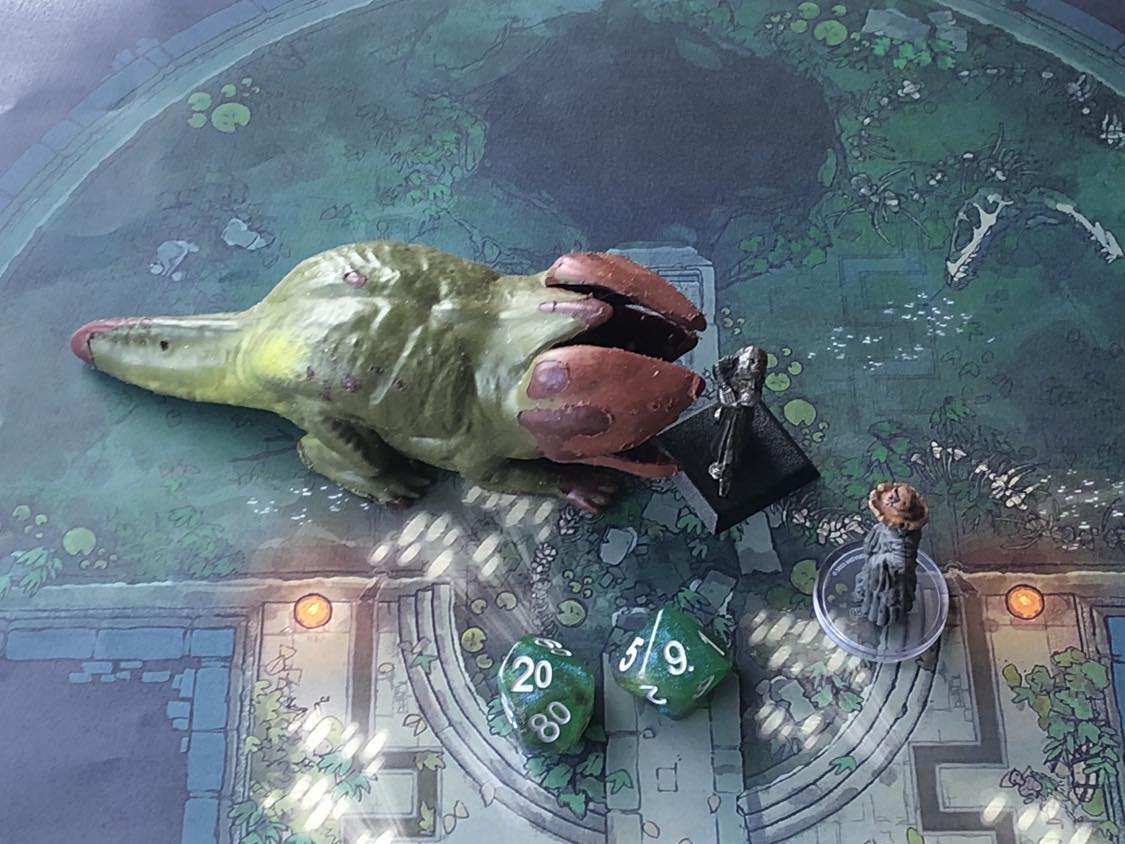 The battle map from above, with the monk fully attacking the creature, and the sorcerer rolling a pair of d10 dice to determine the wild magic surge.