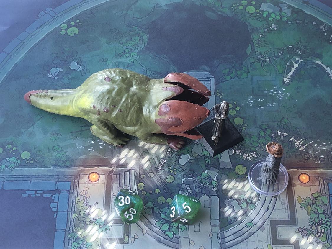 The battle map from above, with the monk fully attacking the creature, and the sorcerer rolling a pair of d10 dice to determine the wild magic surge.