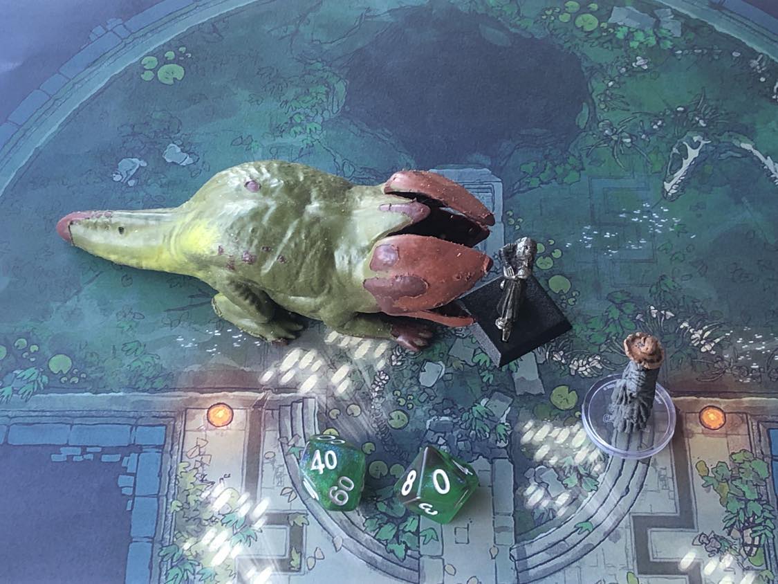 The battle map from above, with the monk fully attacking the creature, and the sorcerer rolling a pair of d10 dice to determine the wild magic surge.